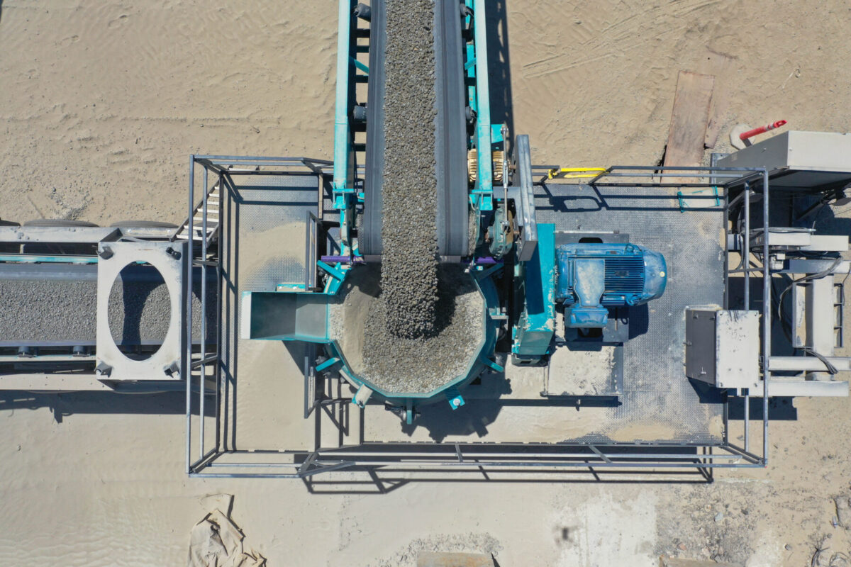Imagen aérea de un sistema transportador y triturador Powerscreen que procesa áridos en bruto para convertirlos en material uniforme en una cantera.